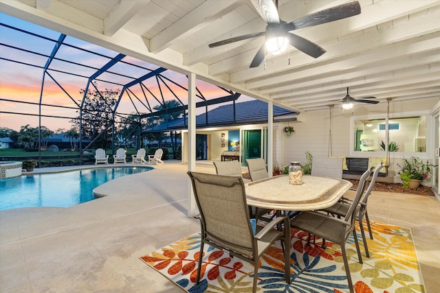 pool at dusk with outdoor dining area, a patio, a pool with connected hot tub, a ceiling fan, and a lanai