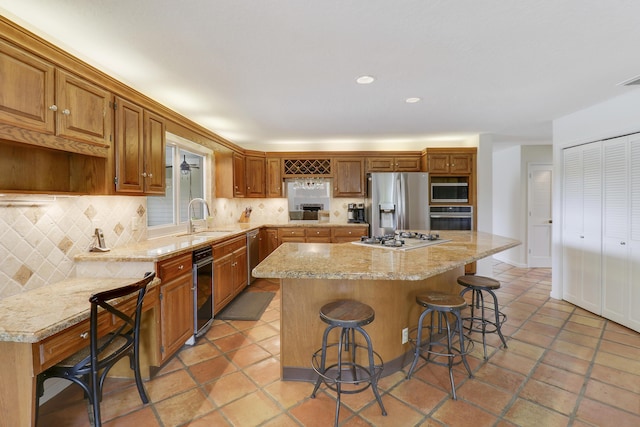 kitchen with appliances with stainless steel finishes, tasteful backsplash, sink, a kitchen island, and a breakfast bar area