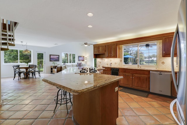 kitchen with decorative backsplash, stainless steel appliances, sink, decorative light fixtures, and a kitchen island