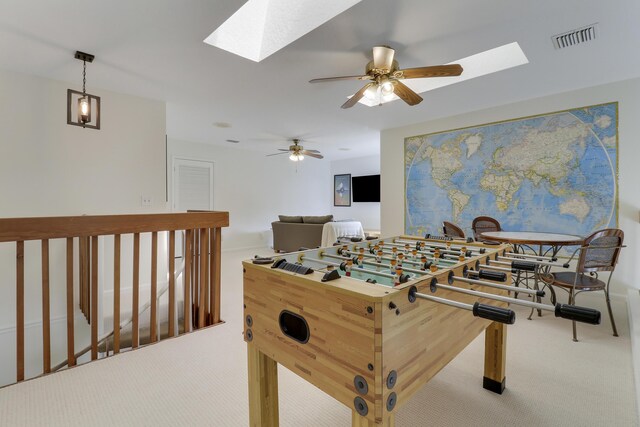 living area with a skylight, visible vents, baseboards, a ceiling fan, and carpet