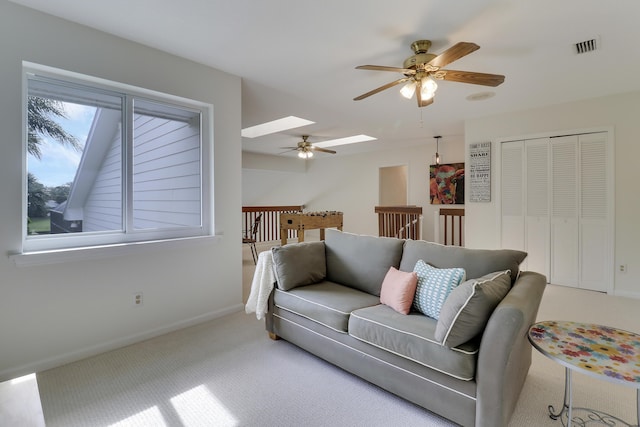 living room with ceiling fan, carpet floors, and a skylight