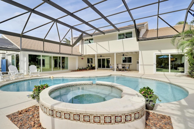 view of pool featuring an in ground hot tub, glass enclosure, ceiling fan, and a patio area