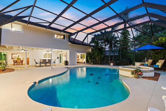 view of pool featuring a patio, glass enclosure, ceiling fan, a pool with connected hot tub, and outdoor dining space