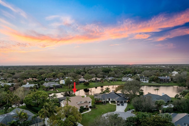 aerial view at dusk featuring a water view and a residential view