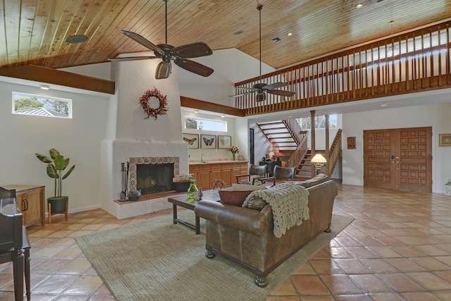 living area featuring a tile fireplace, wooden ceiling, a high ceiling, and stairs