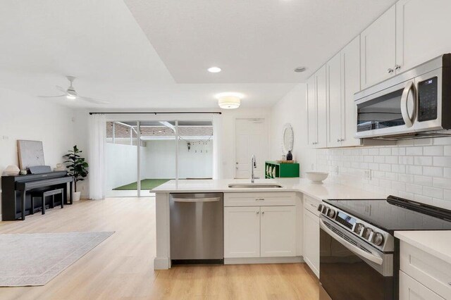 kitchen with sink, appliances with stainless steel finishes, white cabinetry, and light wood-type flooring