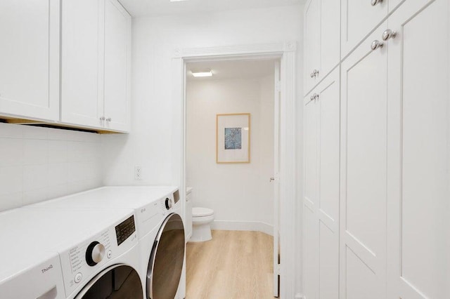 clothes washing area with washer and dryer and light wood-type flooring