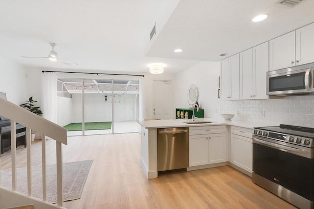 kitchen with sink, appliances with stainless steel finishes, light wood-type flooring, and white cabinets