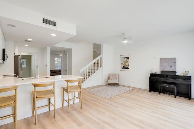 kitchen featuring sink, a kitchen bar, white cabinetry, light hardwood / wood-style floors, and stainless steel appliances