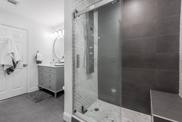 bathroom with tile patterned flooring, vanity, and tiled shower