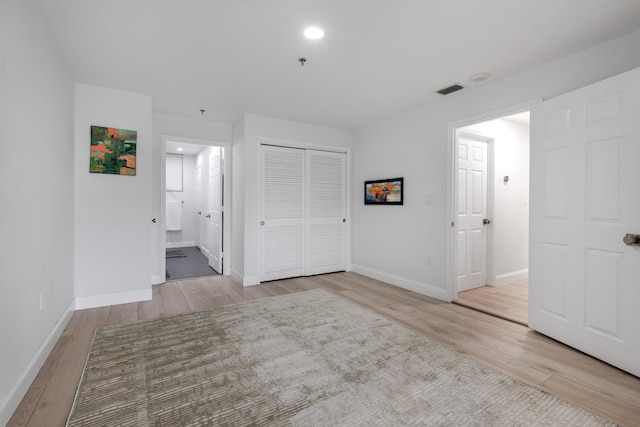 unfurnished bedroom featuring light hardwood / wood-style floors, a closet, and ensuite bath