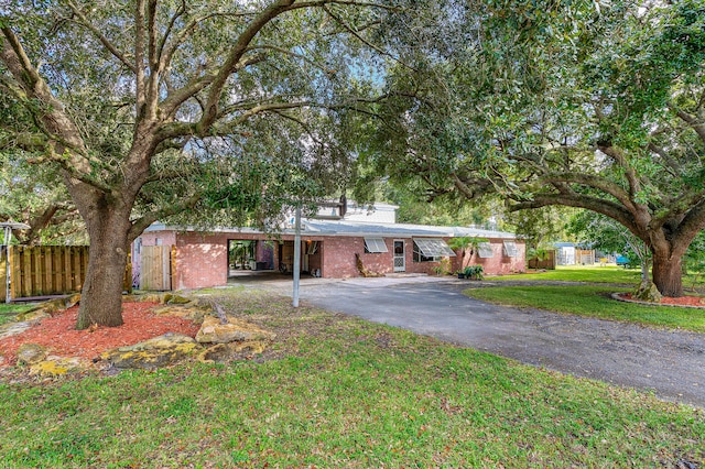 view of front of home featuring a front lawn and a storage shed