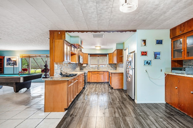 kitchen featuring stainless steel appliances, billiards, backsplash, and hardwood / wood-style floors