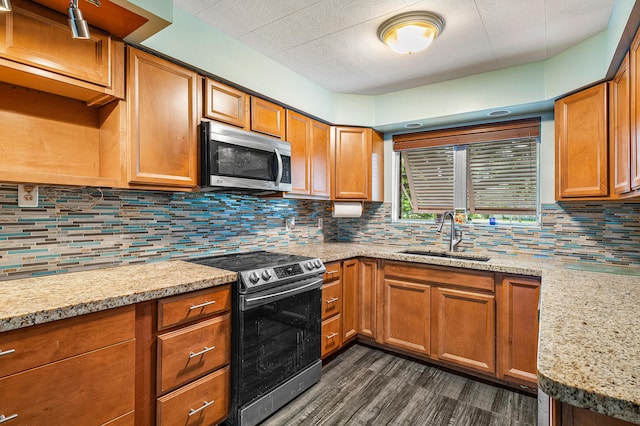 kitchen featuring appliances with stainless steel finishes, dark hardwood / wood-style floors, light stone countertops, decorative backsplash, and sink