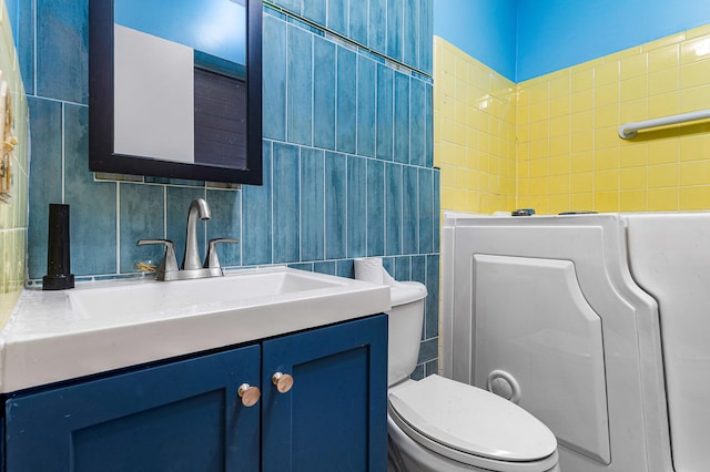 bathroom with tile walls, vanity, and toilet