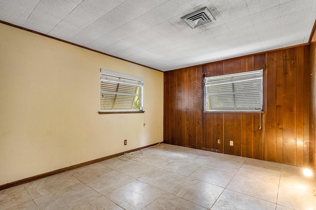 empty room featuring wood walls and ornamental molding