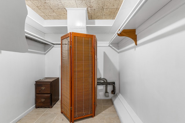 spacious closet featuring a paneled ceiling and light tile patterned floors