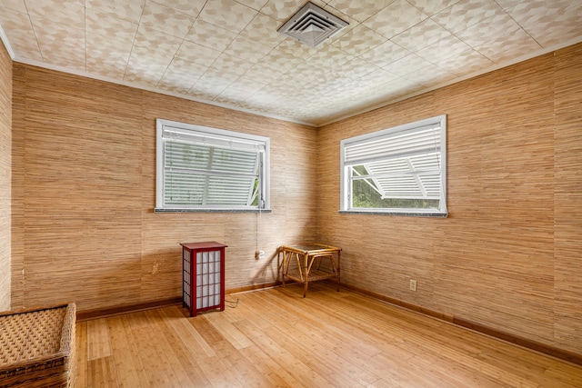 unfurnished room featuring hardwood / wood-style flooring, a healthy amount of sunlight, and wooden walls