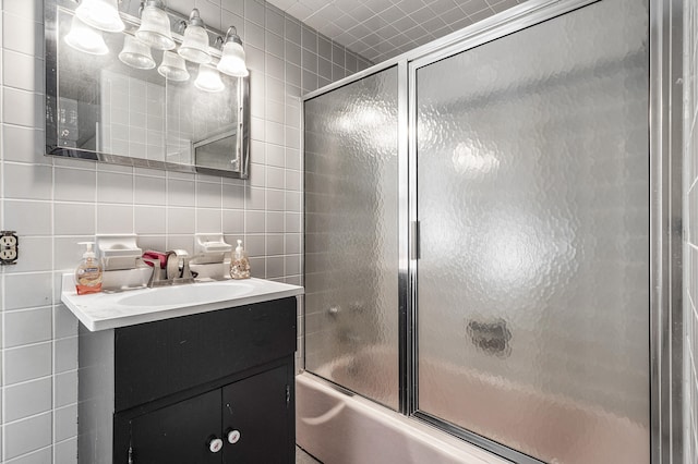 bathroom featuring tile walls, vanity, combined bath / shower with glass door, and tasteful backsplash