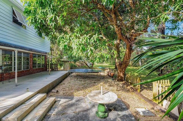 view of yard with a trampoline and a patio