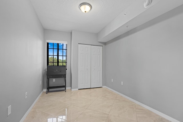 unfurnished bedroom featuring light tile patterned floors, a textured ceiling, and a closet