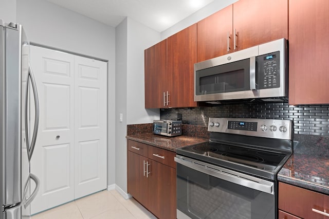 kitchen featuring dark stone counters, light tile patterned flooring, decorative backsplash, and appliances with stainless steel finishes