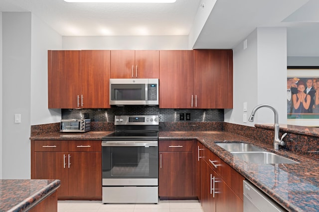 kitchen with decorative backsplash, stainless steel appliances, sink, and dark stone countertops