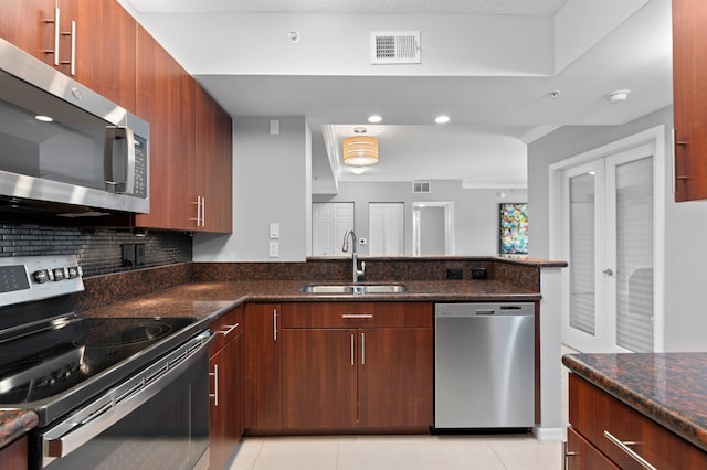 kitchen featuring french doors, appliances with stainless steel finishes, dark stone counters, and sink