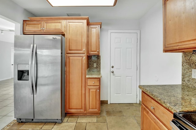 kitchen with tasteful backsplash, light stone countertops, and stainless steel refrigerator with ice dispenser