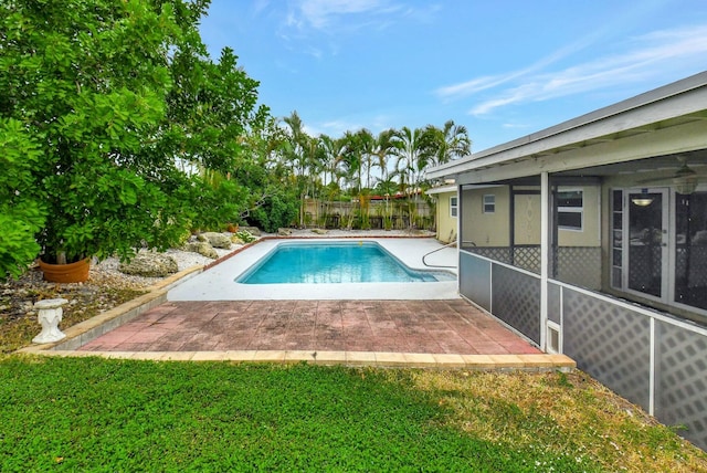 view of pool with a lawn, a sunroom, and a patio