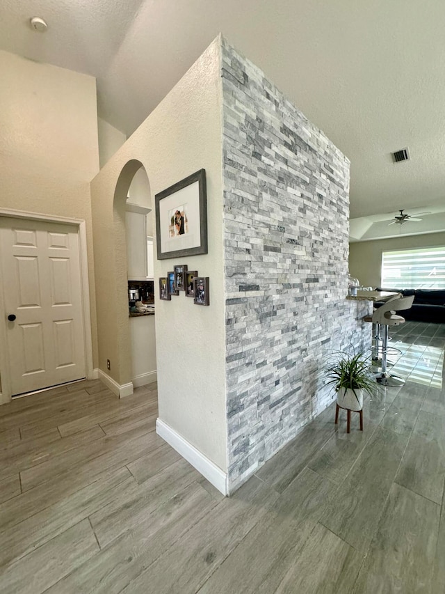 hallway featuring lofted ceiling, wood-type flooring, and a textured ceiling