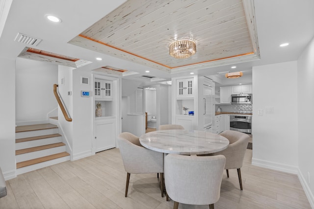 dining room with light wood-type flooring and a raised ceiling