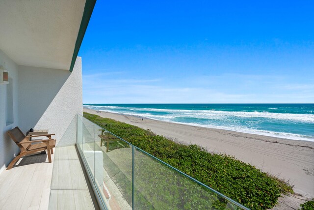 balcony featuring a water view and a beach view