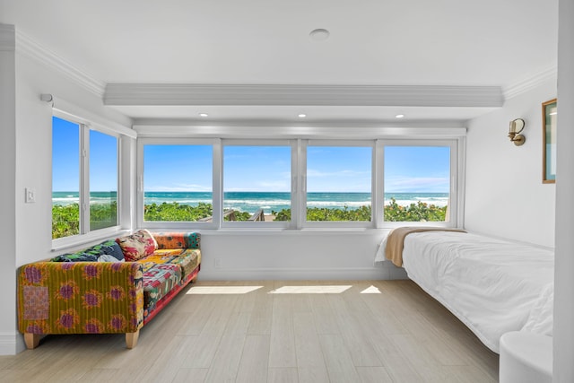 bedroom featuring light hardwood / wood-style floors, crown molding, and a water view