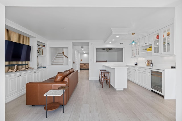 living room with wine cooler, crown molding, light hardwood / wood-style floors, and ceiling fan