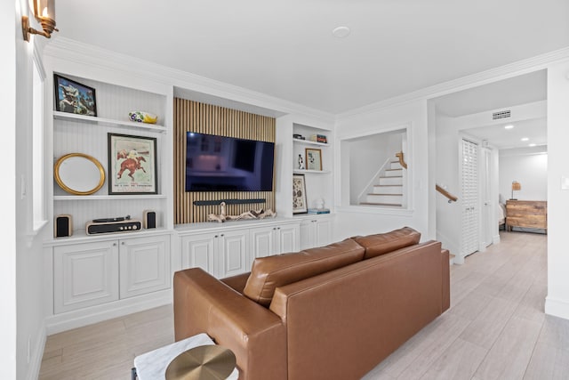 living room with ornamental molding, built in shelves, and light wood-type flooring