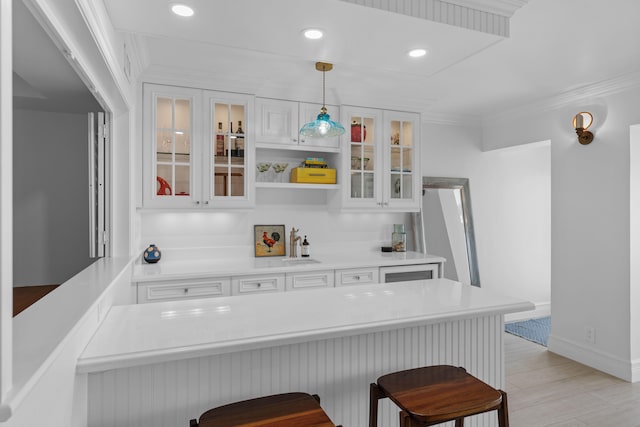 kitchen featuring a kitchen breakfast bar, white cabinets, and hanging light fixtures