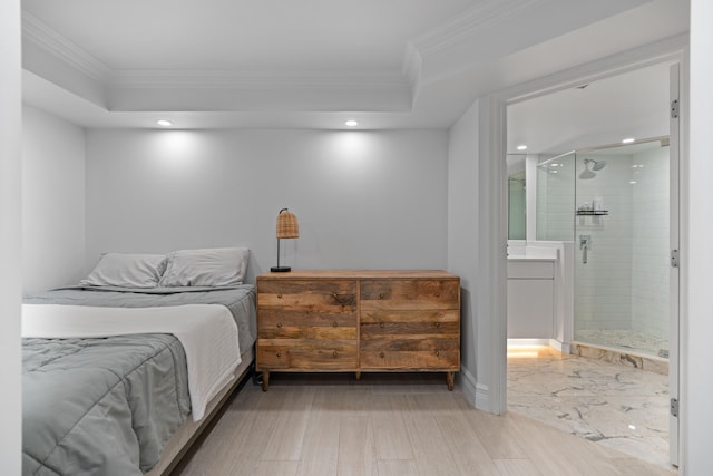 bedroom featuring light hardwood / wood-style flooring, ornamental molding, and ensuite bath