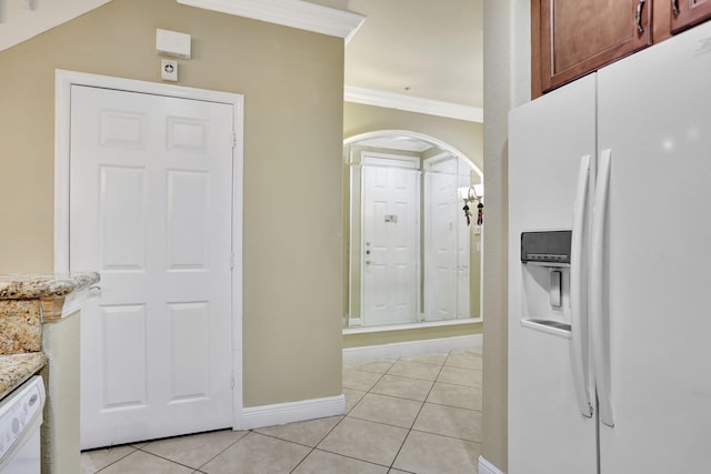 kitchen with crown molding, light stone counters, white appliances, and light tile patterned floors