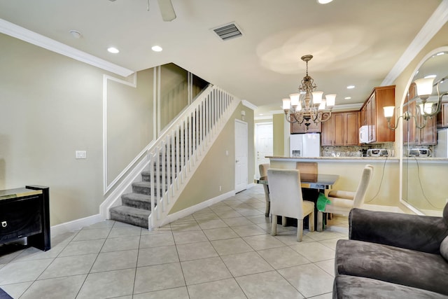 tiled dining room featuring crown molding and a chandelier