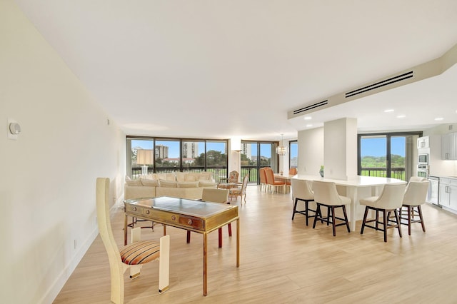 dining area with a wall of windows, a chandelier, and light wood-type flooring