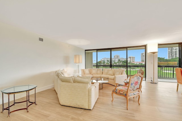 living room with light hardwood / wood-style floors, a healthy amount of sunlight, and floor to ceiling windows