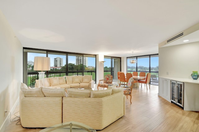 living room featuring wine cooler, an inviting chandelier, light hardwood / wood-style floors, and floor to ceiling windows