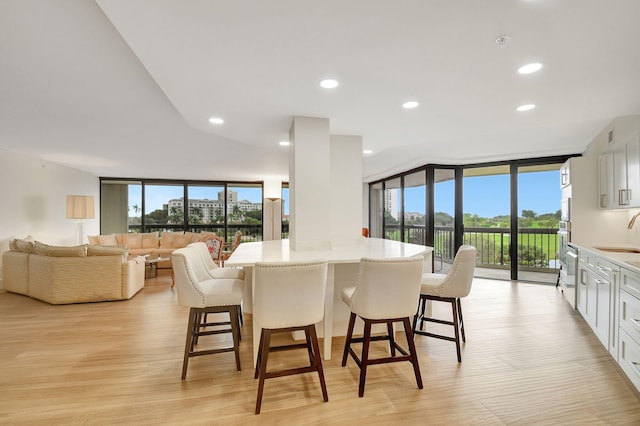 dining room with sink, floor to ceiling windows, and light wood-type flooring