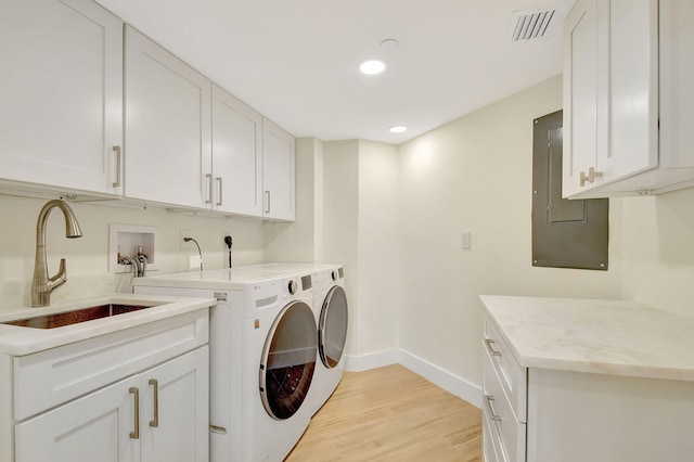 washroom with cabinets, electric panel, light wood-type flooring, independent washer and dryer, and sink