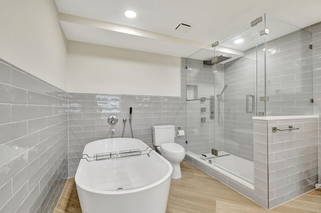 bathroom featuring tile walls, separate shower and tub, hardwood / wood-style flooring, and toilet