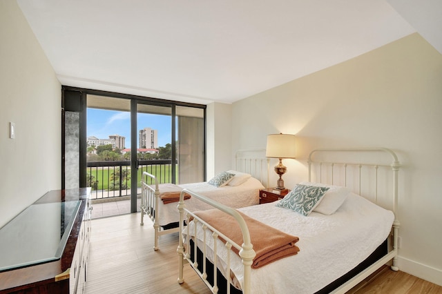 bedroom featuring expansive windows, access to outside, and light wood-type flooring