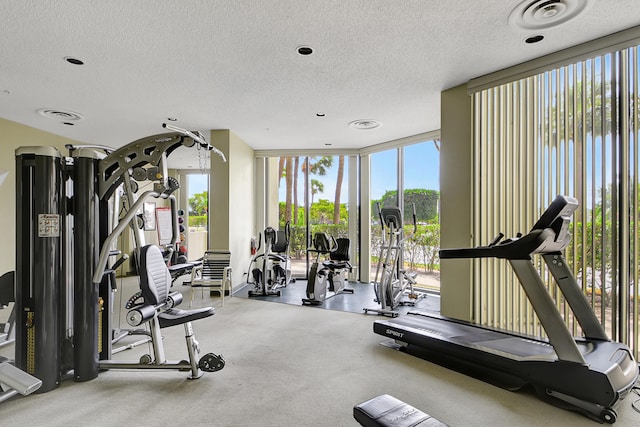 exercise room featuring a wealth of natural light, expansive windows, a textured ceiling, and a water view