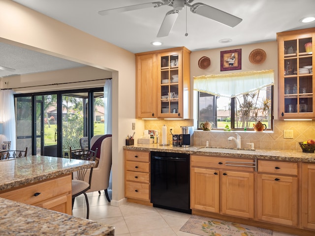 kitchen featuring black dishwasher, backsplash, sink, light stone counters, and ceiling fan