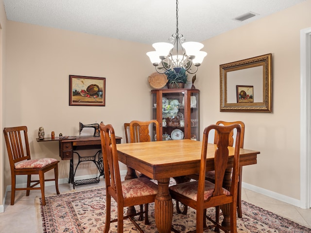 dining area with light tile patterned flooring, a textured ceiling, and an inviting chandelier